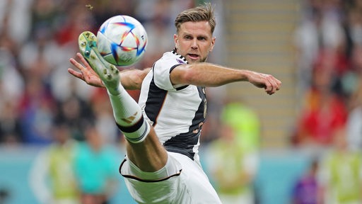 Werder-Stürmer Niclas Füllkrug streckt beim WM-Spiel gegen Spanien sein Bein sehr hoch, um den Ball zu spielen.