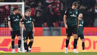 Werder-Spieler um Stürmer Niclas Füllkrug mit hängenden Köpfen auf dem Spielfeld.