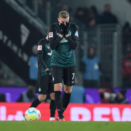 Werder-Stürmer Marvin Ducksch schlägt auf dem Spielfeld frustriert die Hände vors Gesicht.