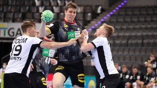 Handball-Nationalspieler Finn Lemke wird von zwei Gegenspielern festgehalten.