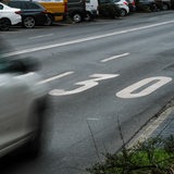 Ein Auto fährt über eine Straße auf der eine große 30 aufgemalt ist.
