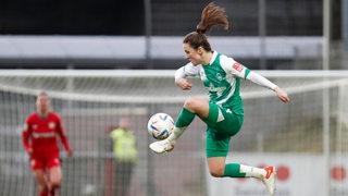 Werders Fußballerin Michaela Brandenburg springt bei einer Ballannahme in die Luft, ihr langer Pferdeschwanz fliegt dabei hoch.