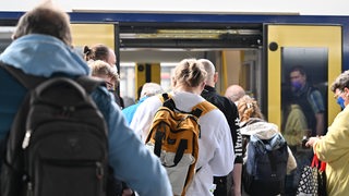 Eine Menschenmenge steht vor einer geöffneten Zugtür.