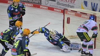 Eishockey-Spieler der Fischtown Pinguins verteidigen mit Goalie Maximilian Franzreb das Tor gegen einen Augsburger Angreifer.