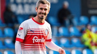 Fußballspieler Fin Bartels lächelt im Trikot von Holstein Kiel.