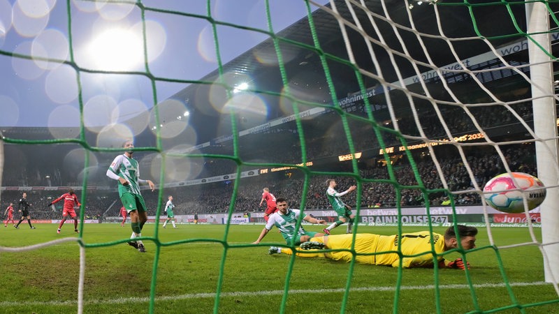 Blick von hinten auf das Werder-Tor beim Gegentreffer von Leverkusen, Torwart Jiri Pavlenka liegt hilflos am Boden, Werder-Spieler schauen ratlos, wie der Ball im Netz zappelt.