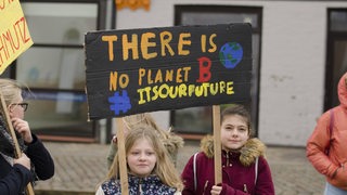 Zwei Mädchen halten ein Plakat in der Hand mit der Aufschrift "There is no planet B".