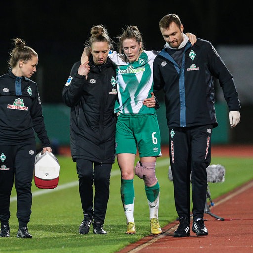 Werder-Spielerin Reena Wichmann wird von zwei Betreuern gestützt und mit dicker Bandage am Knie vom Spielfeld geführt.