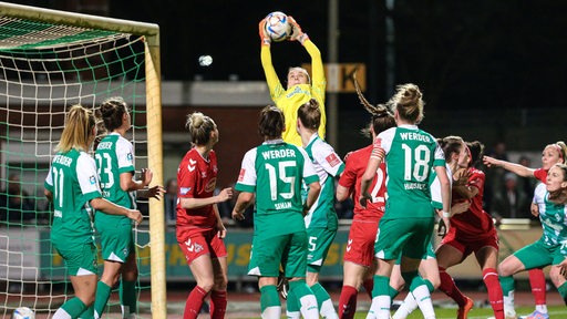 Werder-Torhüterin Anneke Borbe springt im Getümmel vor ihrem Tor hoch und schnappt sich den Ball.