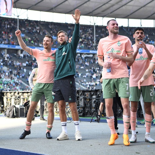 Werder-Spieler Christian Groß Arm in Arm mit Niclas Füllkrug, winken den Fans auf der Tribüne nach dem Sieg zu.