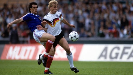 DFB-Stürmer Jürgen Klinsmann im Laufduell mit seinem jugoslawischen Gegenspieler.