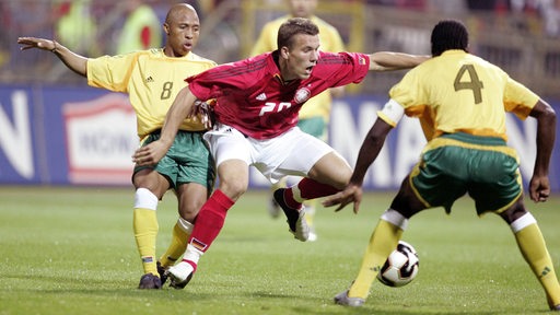 DFB-Angreifer Lukas Podolski setzt sich gegen zwei südafrikanische Gegenspieler durch.