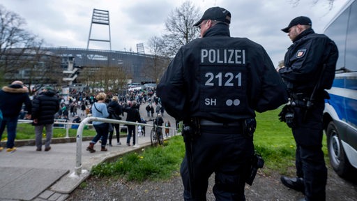 Zwei Polizisten beobachten die Fans, die vor einem Bundesliga-Spiel ins Weser-Stadion strömen.