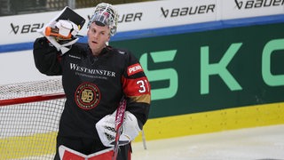 Der deutsche Eishockey-Nationaltorhüter Maximilian Franzreb spritzt sich Wasser aus einer Trinkflasche ins Gesicht.