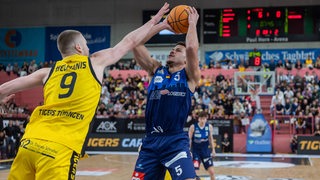 Basketball-Spieler Jarelle Alexander Reischel von den Eisbaeren Bremerhaven wird beim Wurf von einem Tübinger Spieler attackiert.