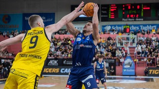 Basketball-Spieler Jarelle Alexander Reischel von den Eisbaeren Bremerhaven wird beim Wurf von einem Tübinger Spieler attackiert.