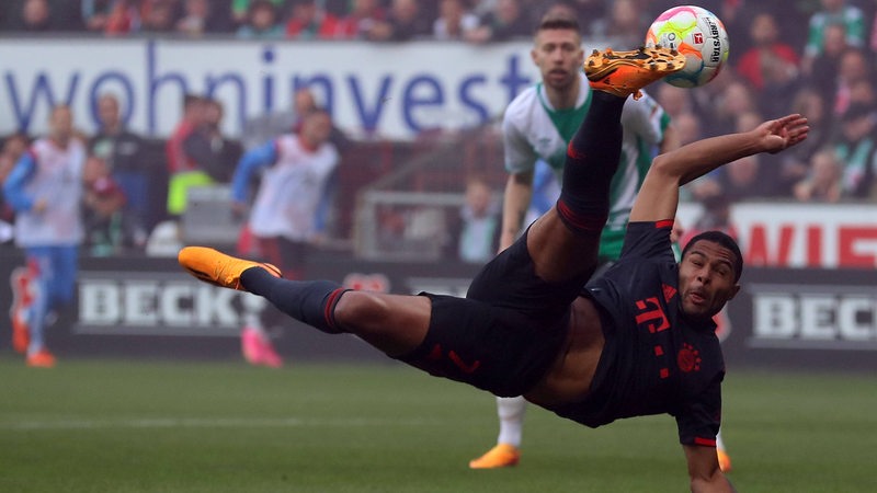 Bayern-Spieler Serge Gnabry liegt beim Torschuss waagerecht in der Luft.