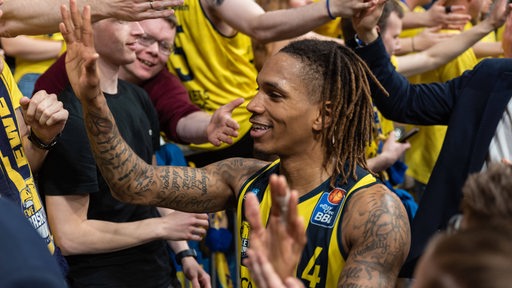 Basketballer Dewayne Russel von den Baskets Oldenburg genießt das Bad in der Menge und klatscht bei den Fans ab.