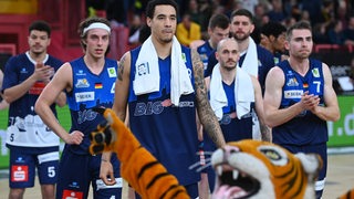 Basketball-Spieler der Eisbären Bremerhaven stehen nach der Niederlage gegen die Tigers Tübingen enttäuscht auf dem Parkett, das Tiger-Maskottchen feiert vor ihnen.