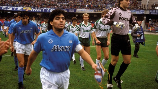 Diego Armando Maradona läuft mit dem SSC Neapel ins Weser-Stadion ein, im Hintergrund blickt ihn Dieter Eilts grimmig an.