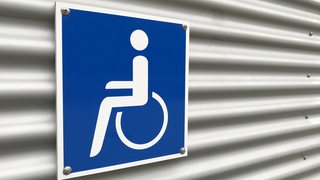 Ein blaues Schild mit einem weißen Rollstuhlfahrer-Piktogramm