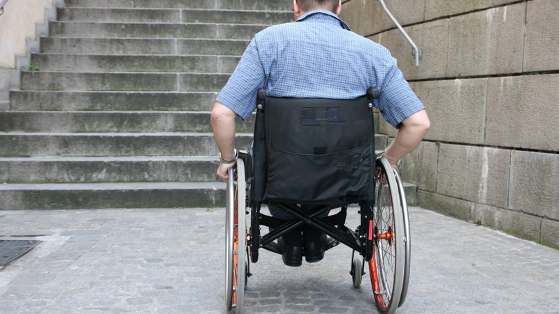Ein Mann im Rollstuhl vor einer Treppe. (Archivbild)