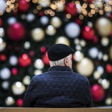 Ein Mann sitzt allein auf einer Bank vor einem geschmückten Weihnachtsbaum (Symbolbild)