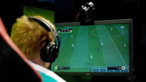 Michael "MegaBit" Bittner spielt das Computerspiel FIFA und trägt ein Headset. 