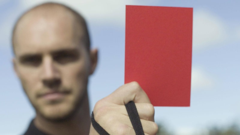 Ein Schiedsrichter hält eine Rote Karte in die Kamera