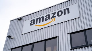 Das Amazon-Logo hängt an einem Gebäude.