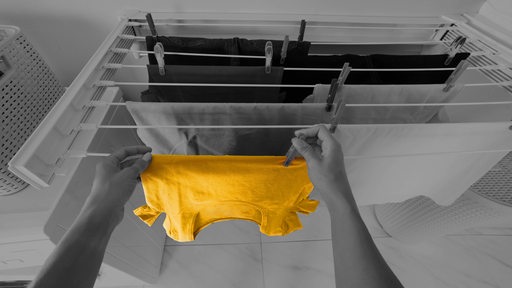 Hände hängen gewaschene Wäsche auf einen Wäscheständer.