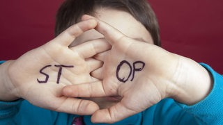 auf Kinderhänden steht das Wort STOP