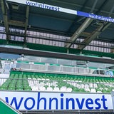 Wohninvest-Schriftzug vor Sitzplatztribüne im Weser-Stadion. 