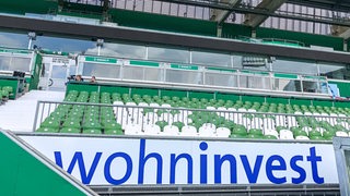 Wohninvest-Schriftzug vor Sitzplatztribüne im Weser-Stadion. 
