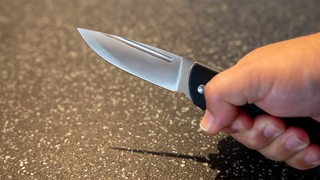 Eine Person hält ein Messer in der Hand.