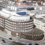 Blick aus der Luft auf ein braunes Backsteingebäude, das die Form eines Schiffes hat.