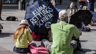 Klimademonstranten sitzen auf dem Boden