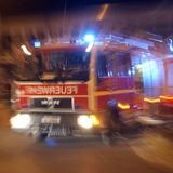 Ein Feuerwehrwagen fährt nachts mit Blaulicht zu einem Einsatz.