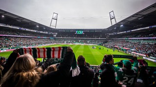 Werder-Fans halten im Weser-Stadion ihre Schals hoch.