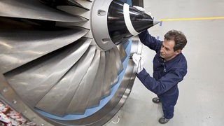 Ein Airbus-Mitarbeiter steht an einem Triebwerk in einer Montagehalle