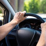 Die Hände einer Seniorin am Lenkrad eines Autos (Symbolbild)