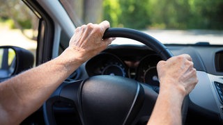 Die Hände einer Seniorin am Lenkrad eines Autos (Symbolbild)