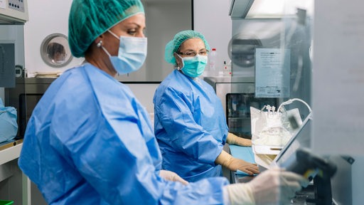 Zwei Frauen in medizinischer Schutzkleidung in einem Labor.