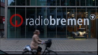 Eine Frau fährt auf einem Fahrrad vor dem Funkhaus von Radio Bremen entlang.