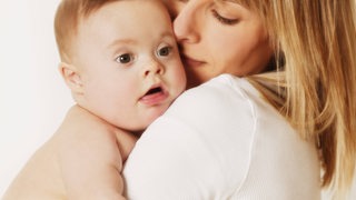 Eltern mit einem Downsyndrom-Baby auf dem Arm (Symbolbild).
