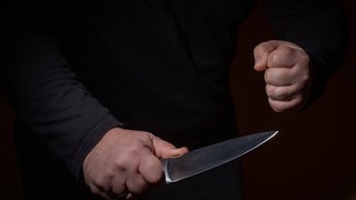 Eine geballte Faust neben einem gezücktem Messer.
