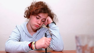 Ein jugendliches Mädchen guckt traurig beim Homeschooling (Symbolbild)