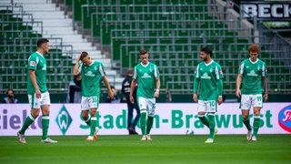 Die Werder-Spieler Milos Veljkovic, Maximilian Eggestein Marco Friedl, Leonardo Bittencourt und Josh Sargent stehen enttäuscht auf dem Rasen des Weser-Stadions.