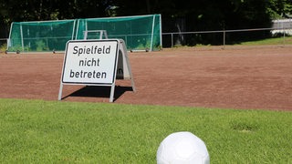 Leerer Fußballplatz mit einem weißen Schild mit der Aufschrift "Spielfeld nicht betreten".