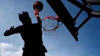 Ein Mann wirft einen Basketball, während er in der Luft steht.